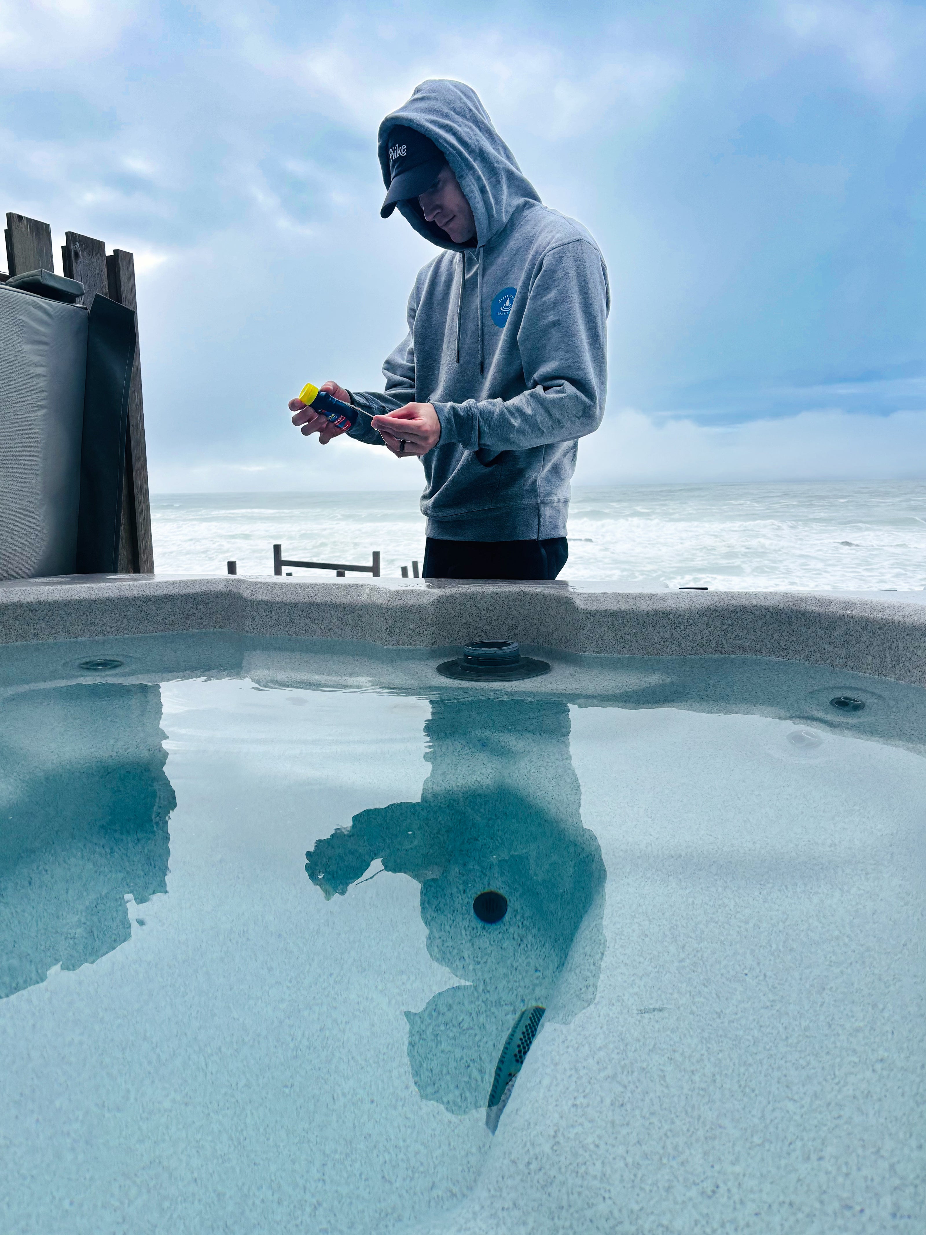 Person standing by a hot tub checking the spa chemicals with a scenic background